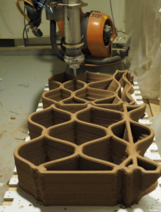 image of 3d printing robot making curvy cellular forms out of clay